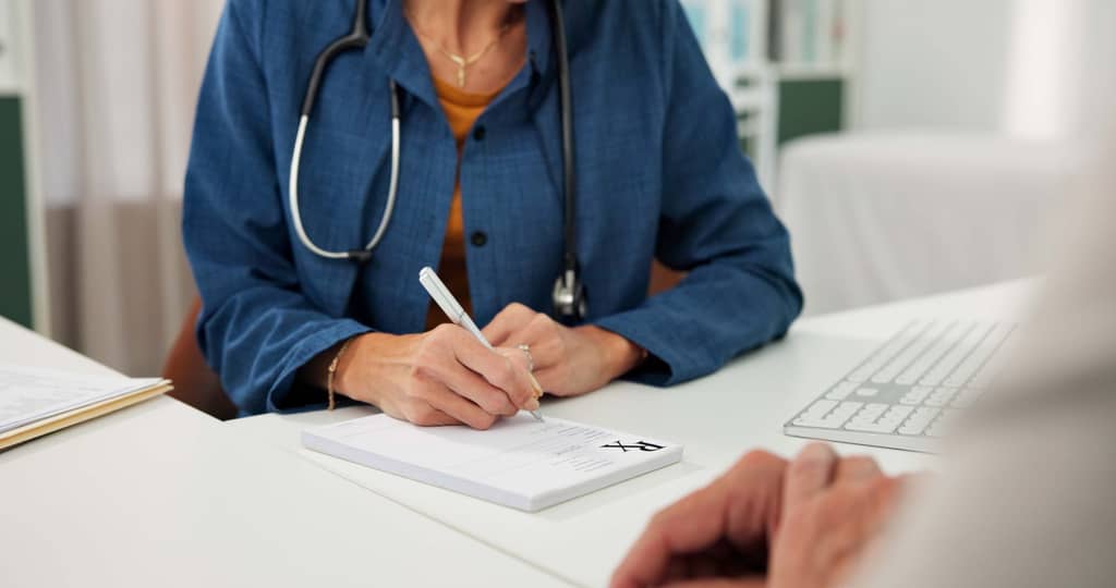 GP writing a referral letter for a patient during a UK surgery appointment