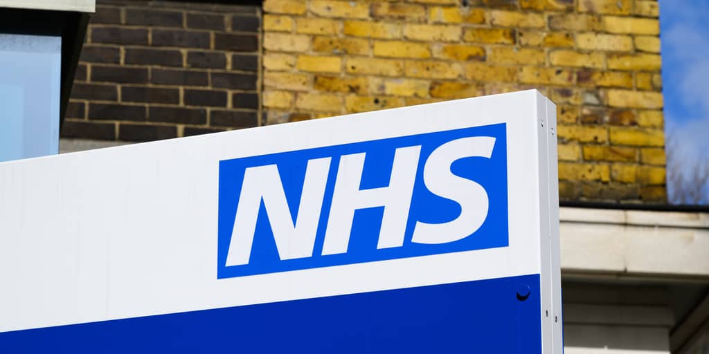 Two doctors consulting patients, comparing NHS and private GP appointments in the UK