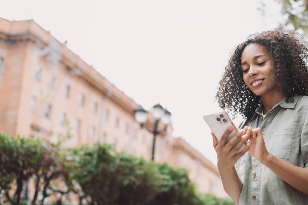 Woman checks her health insurance app on a smartphone while walking through a city street