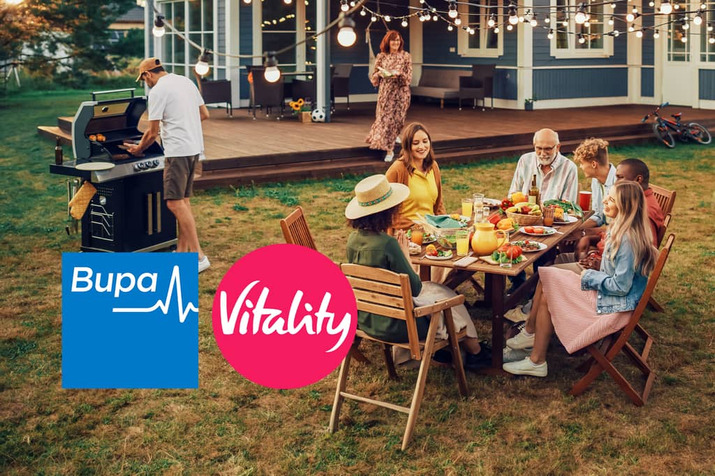 Family gather for a garden barbecue around an outdoor table, with the Bupa and Vitality logos overlaid