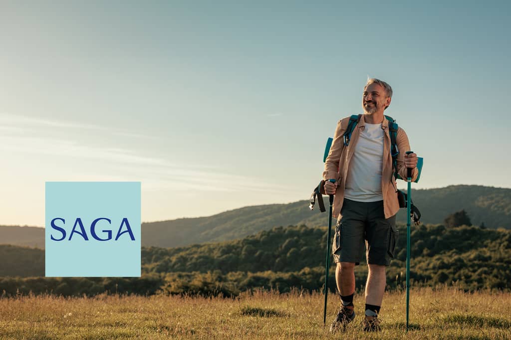 Smiling older man hiking across a hillside at sunset, with the Saga logo overlaid