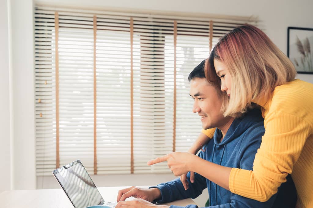 Couple looking at a laptop together at a table while reviewing finances at home