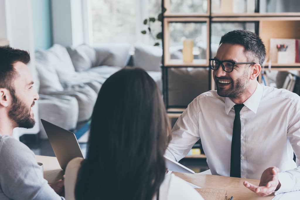 Health insurance broker talking with a couple across a table at home