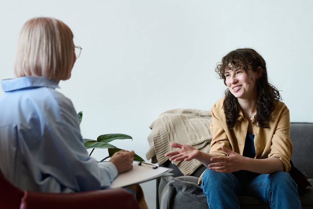 Woman talking to a therapist holding a clipboard during a counselling session
