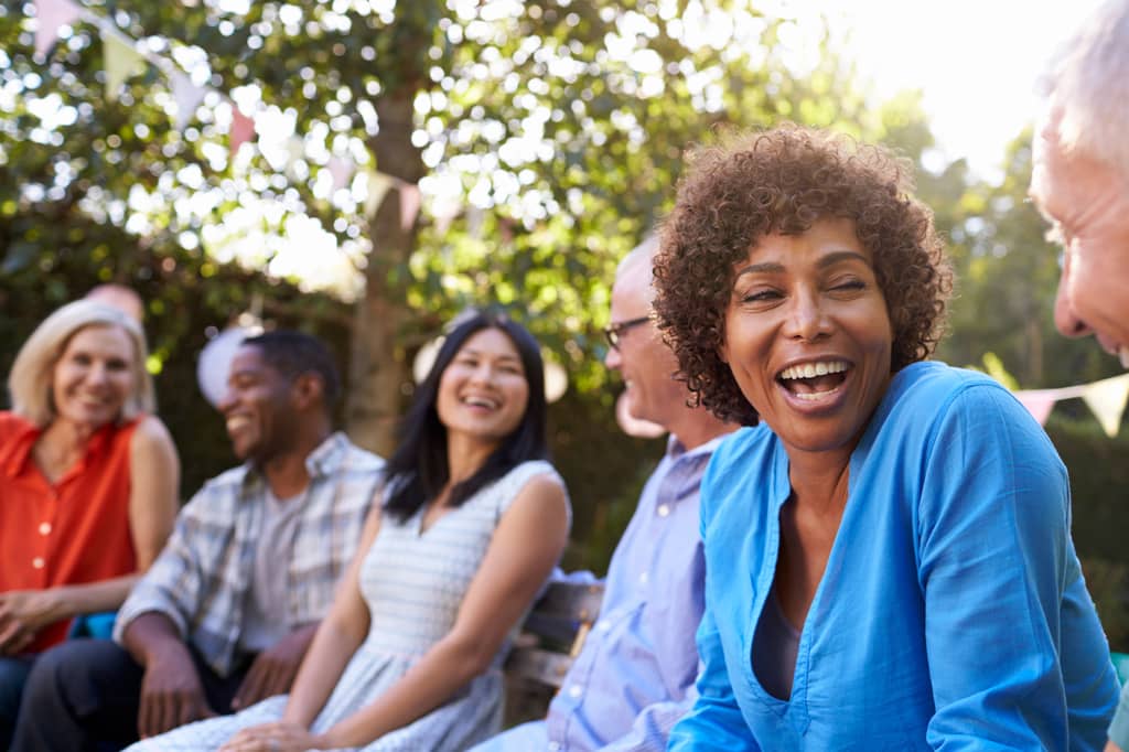 Mature woman laughing with friends at an outdoor gathering