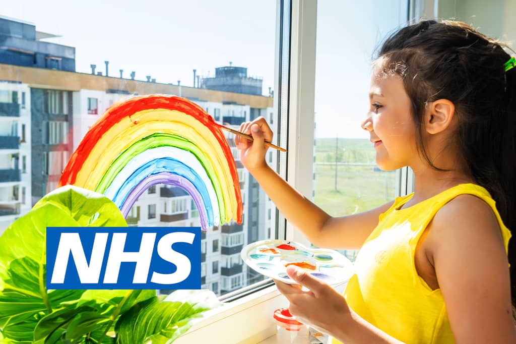 Young girl paints a colourful rainbow on a window, with the NHS logo overlaid