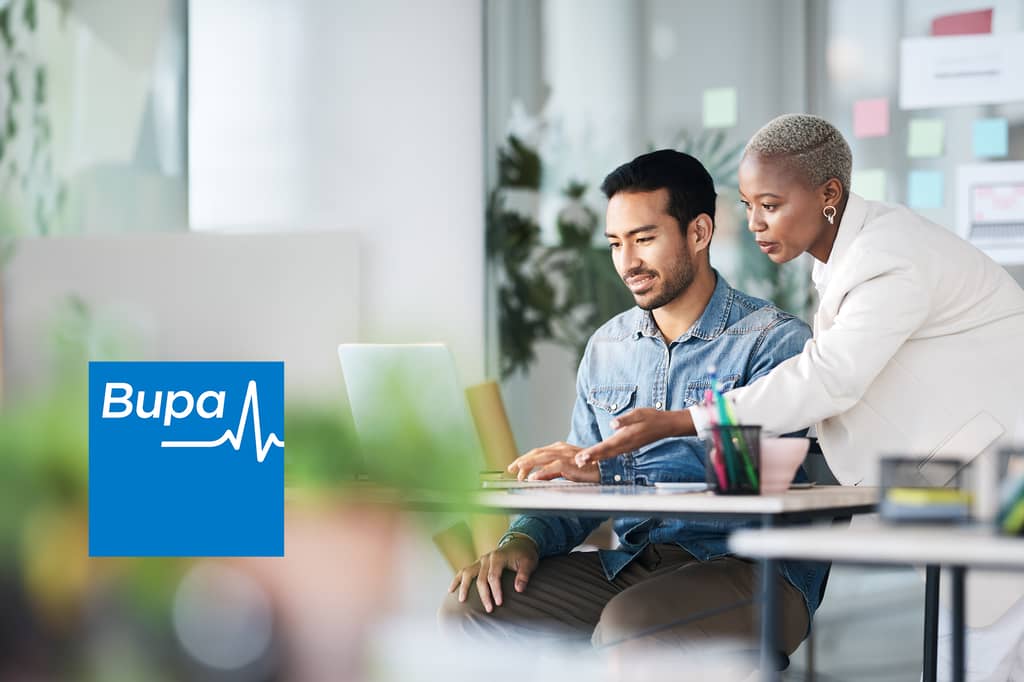 Two colleagues work at a laptop in an office, with the Bupa logo overlaid