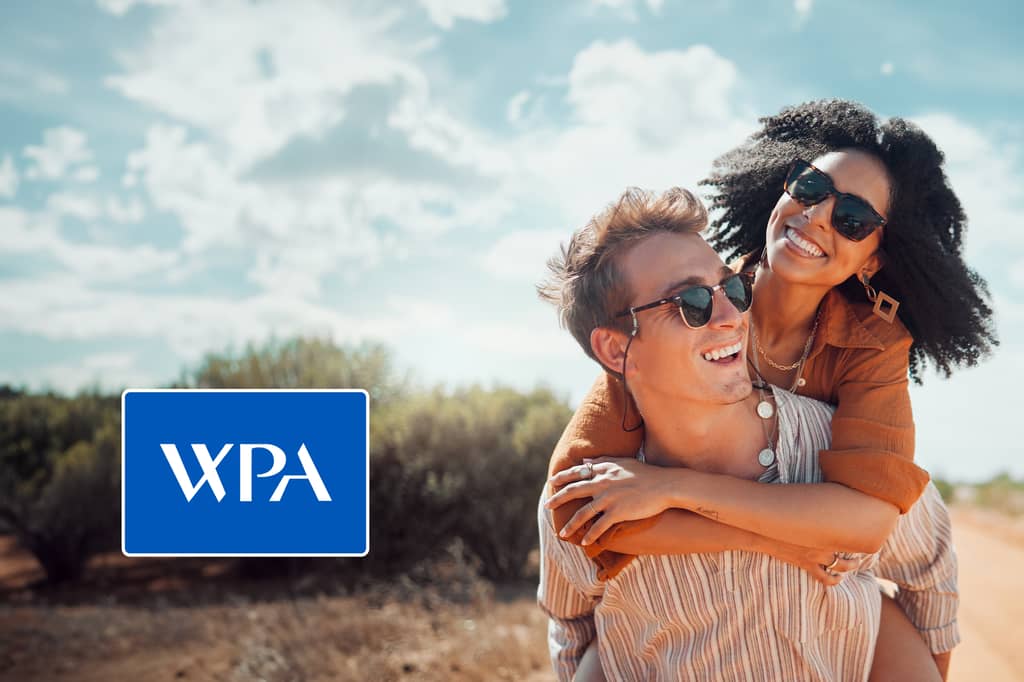 Couple in sunglasses laughing during a piggyback ride outdoors, with the WPA logo overlaid