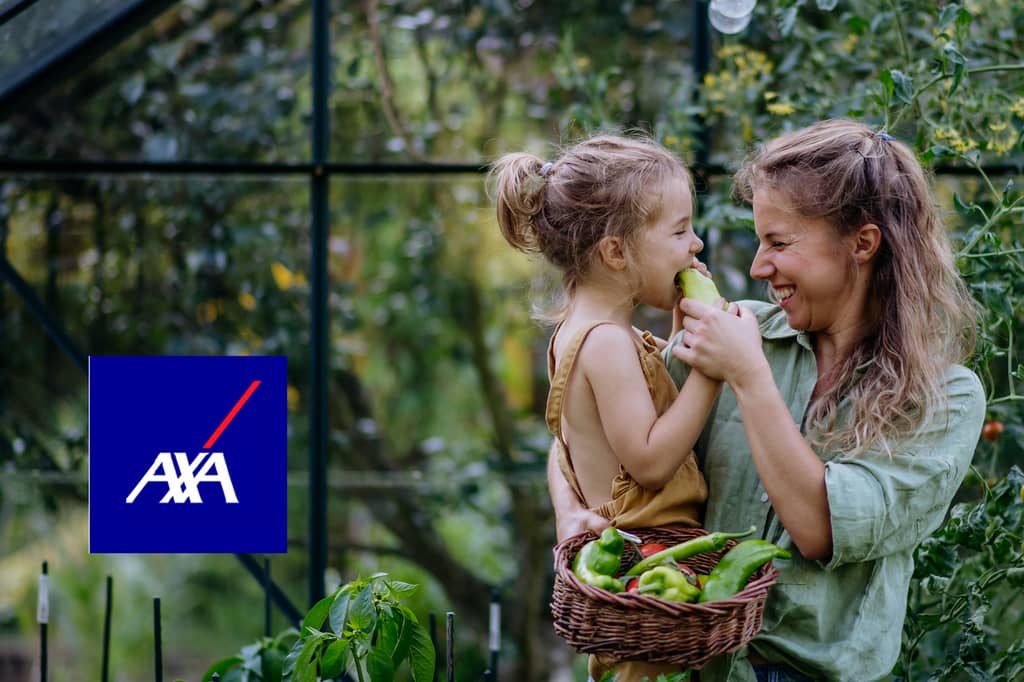 Mother and young daughter laugh in a greenhouse holding peppers, with the AXA logo overlaid